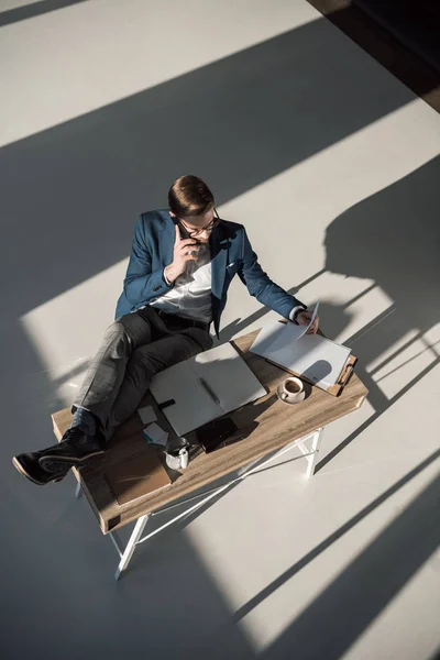 Vista ad alto angolo di uomo d'affari che parla su smartphone mentre si siede sul posto di lavoro — Foto stock