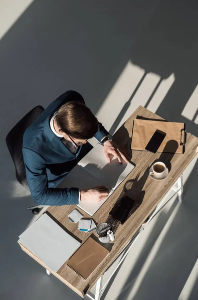 Вид зверху стильного бізнесмена, що пише в блокноті на робочому місці — стокове фото