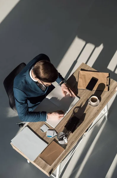 Overhead view of stylish businessman writing in notebook at workplace — Stock Photo