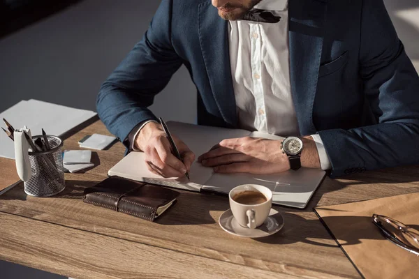 Cropped shot of businessman writing in diary while sitting at table — Stock Photo