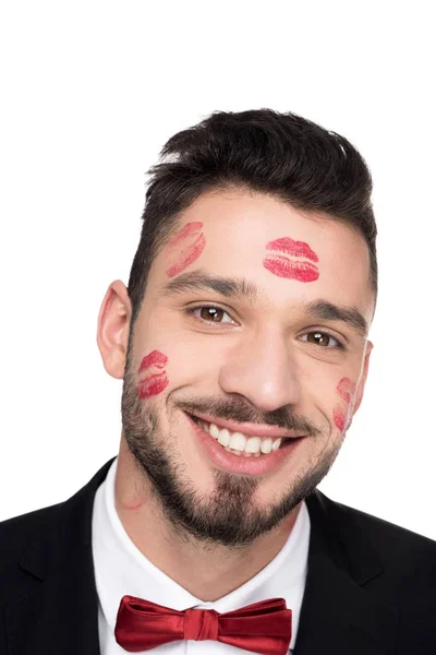 Sonriente hombre guapo con los labios rastros en la cara mirando a la cámara aislada en blanco - foto de stock