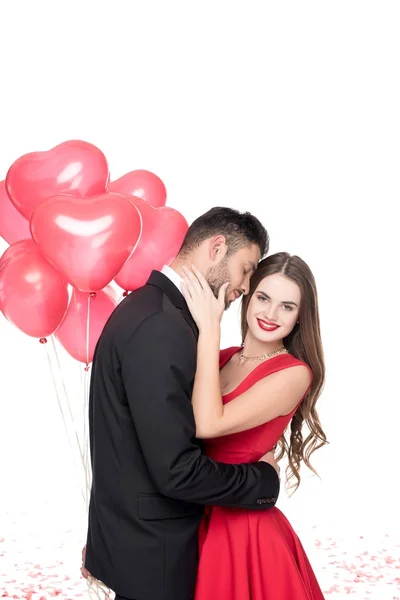 Boyfriend with heart shaped balloons hugging girlfriend isolated on white, valentines day concept — Stock Photo