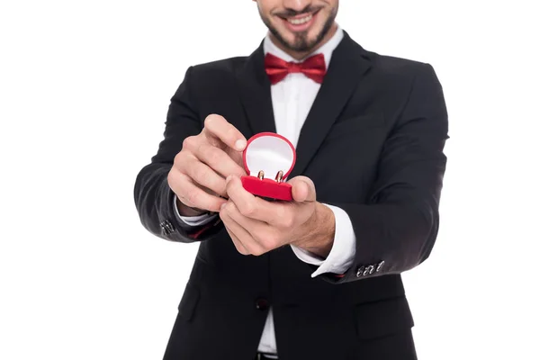 Imagem cortada de homem bonito mostrando caixa vermelha com anéis de casamento isolado no branco — Fotografia de Stock