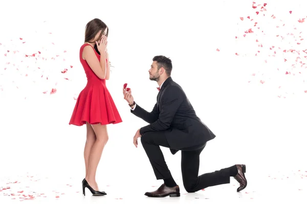Vue latérale du petit ami proposant petite amie et debout sur le genou isolé sur blanc, concept de Saint Valentin — Photo de stock