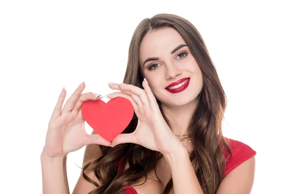 Niña sonriente en vestido rojo mostrando corazón de papel aislado en blanco, concepto de día de San Valentín - foto de stock