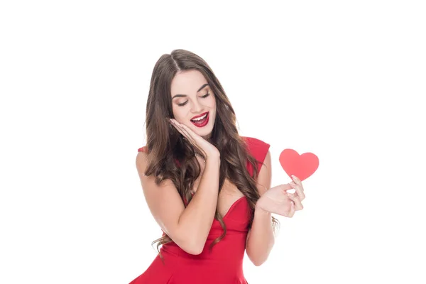 Усміхнена дівчина в червоній сукні тримає паперове серце ізольовано на білому, концепція дня валентинки — стокове фото