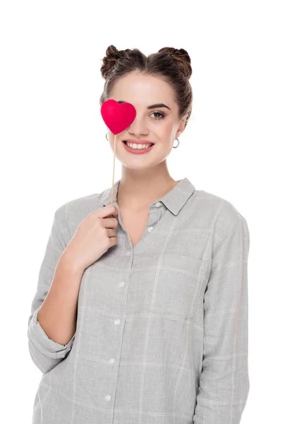 Smiling girl covering eye with paper heart isolated on white, valentines day concept — Stock Photo