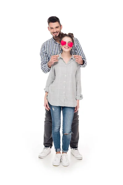 Novio cubriendo novias ojos con corazones de papel en blanco, San Valentín concepto de día - foto de stock