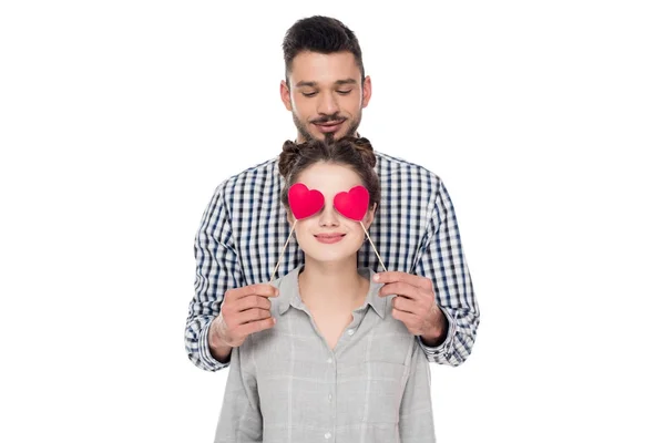 Boyfriend covering girlfriends eyes with paper hearts isolated on white, valentines day concept — Stock Photo