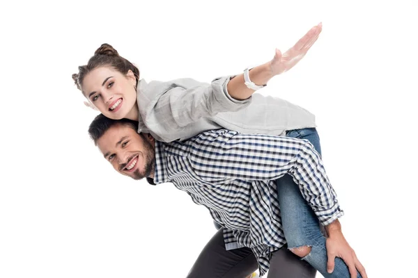 Vista lateral de novio dando piggyback a novia con los brazos abiertos aislados en blanco - foto de stock