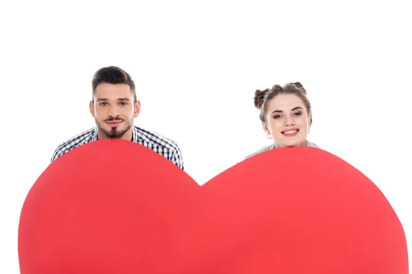 Coppia sorridente guardando fuori dal grande cuore isolato su bianco, concetto di giorno di San Valentino — Foto stock