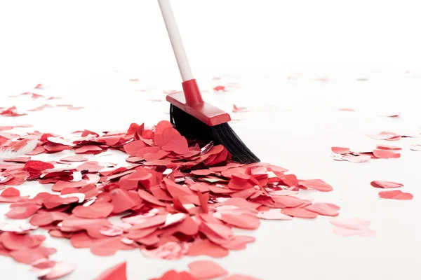 Broom sweeping out heart shaped confetti isolated on white, valentines day concept — Stock Photo