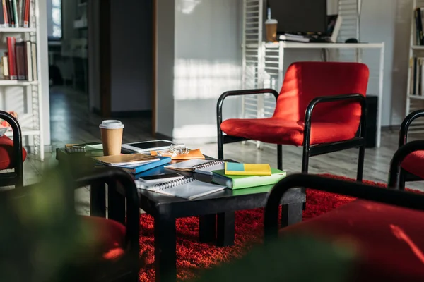 Cuadernos con libros y taza de café desechable en la mesa - foto de stock