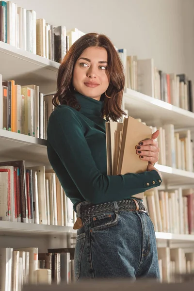 Beautiful girl holding books and looking away — Stock Photo