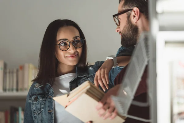 Coppia multiculturale che si guarda in biblioteca — Foto stock