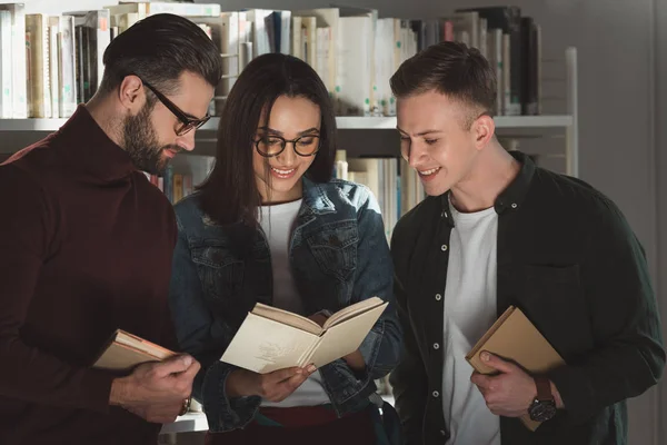 Multicultural students looking at book in library — Stock Photo