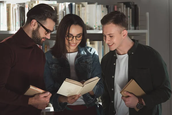 Мультикультурні студенти дивляться на книгу в бібліотеці — стокове фото