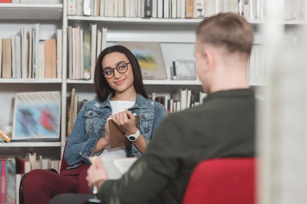 African american girl looking at man in library — Stock Photo