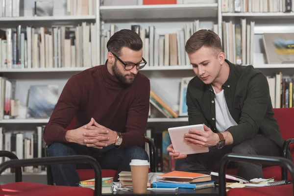 Friends studying together with tablet in library — Stock Photo