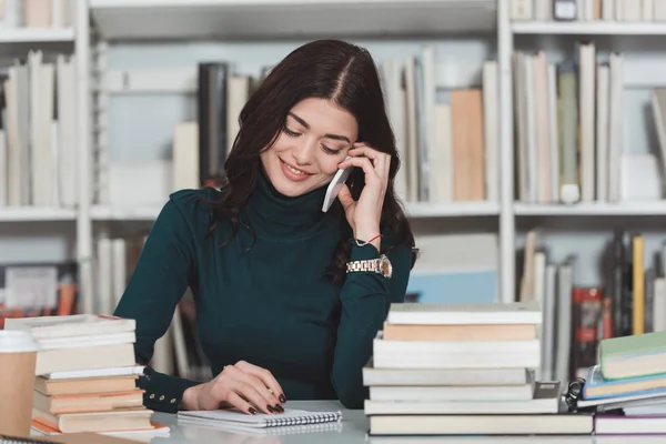 Красива дівчина розмовляє по смартфону в бібліотеці — стокове фото