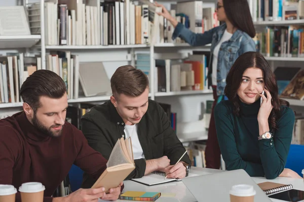 Studente donna che parla con lo smartphone in biblioteca — Foto stock