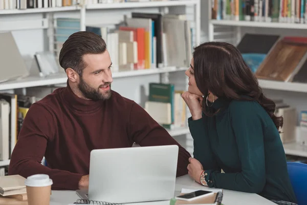 Girlfriend looking at handsome boyfriend in library — Stock Photo