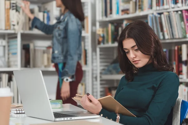 Жінка студент читає книгу в бібліотеці — стокове фото