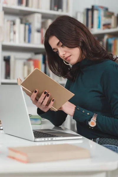 Estudiante mujer leyendo libro en la biblioteca - foto de stock