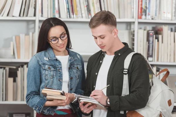Multicultural students looking at notebook in library — Stock Photo