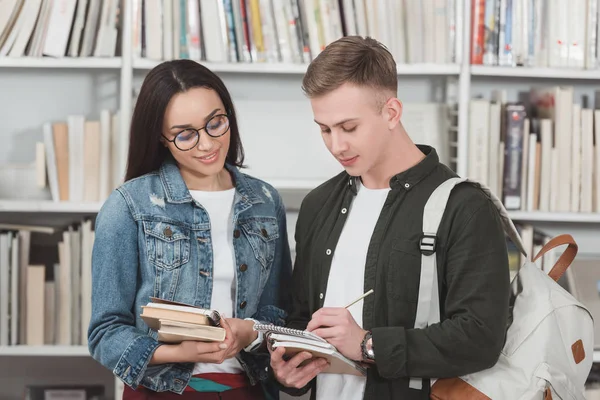 Estudantes multiculturais olhando para notebook na biblioteca — Fotografia de Stock