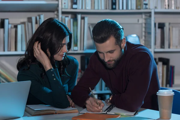 Masculino um estudantes do sexo feminino se preparando para exame na biblioteca no final da noite — Fotografia de Stock