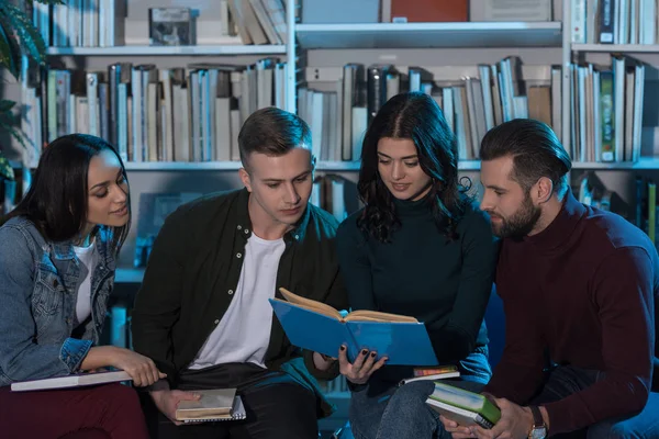 Estudiantes multiculturales leyendo libro y preparándose para el examen - foto de stock