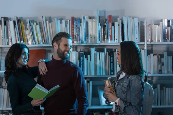 Estudiantes multiculturales felices con libros en la biblioteca - foto de stock