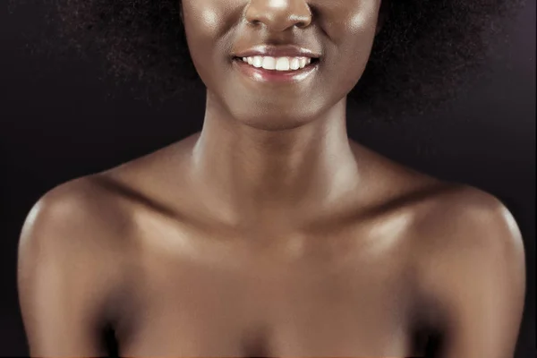 Обрезанный снимок улыбающейся африканской женщины, изолированной на черном — стоковое фото