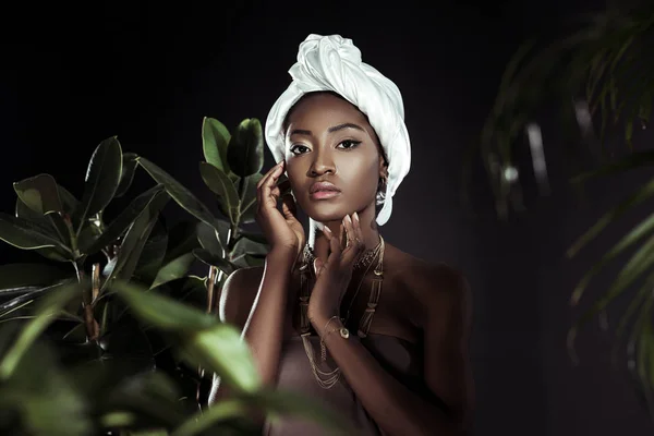 Young african american woman in white wire head wrap behind leaves — Stock Photo