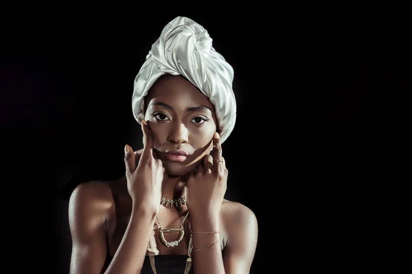 Hermosa mujer afroamericana en envoltura de cabeza de alambre blanco y accesorios de oro aislados en negro - foto de stock