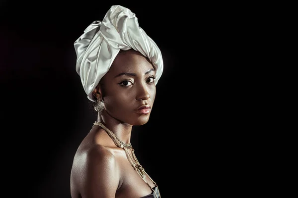 Atractiva mujer afroamericana en envoltura de cabeza de alambre blanco aislado en negro - foto de stock