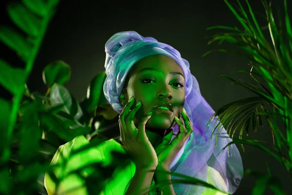 Mujer afroamericana sensual en envoltura de cabeza de alambre tradicional bajo luz verde - foto de stock