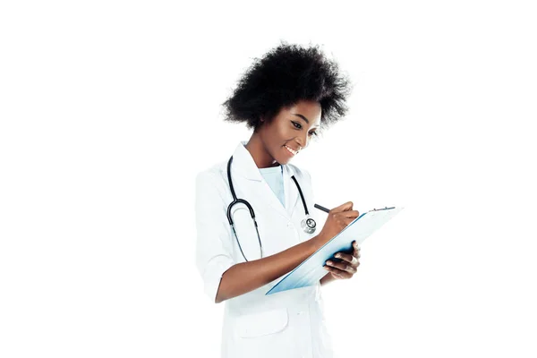 Joven doctora escribiendo diagnóstico en portapapeles aislado en blanco - foto de stock