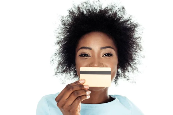 Молода жінка тримає золоту кредитну картку перед обличчям ізольовано на білому — стокове фото