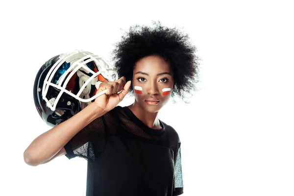 Atractivo jugador de fútbol americano femenino con cara pintada sosteniendo casco aislado en blanco - foto de stock