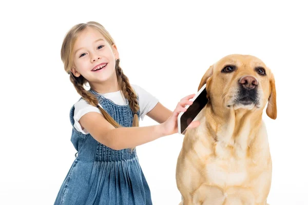 Entzückende fröhliche Kind gibt Smartphone an Hund, isoliert auf weiß — Stockfoto