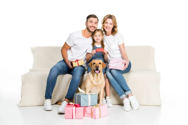 Щаслива сім'я і собака, сидячи на дивані з подарунками, ізольовані на білому — стокове фото