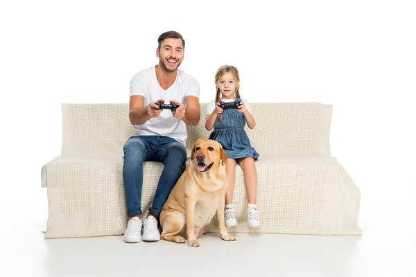 Pai e filha jogando videogame com joysticks enquanto o cão sentado perto, isolado no branco — Fotografia de Stock
