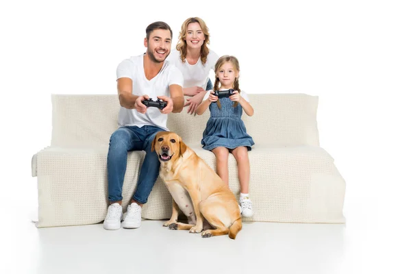 Família feliz jogando videogame com joysticks enquanto cão sentado perto, isolado no branco — Fotografia de Stock