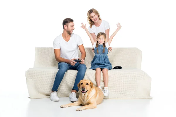 Familia emocionada jugando videojuego con joysticks mientras perro sentado cerca, aislado en blanco - foto de stock