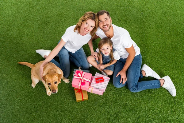 High angle view of family with wrapped gifts sitting on green grass — Stock Photo