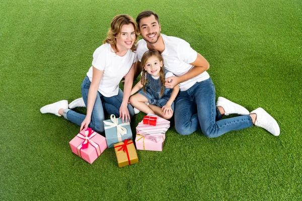 High angle view of family with wrapped gifts sitting on green grass — Stock Photo
