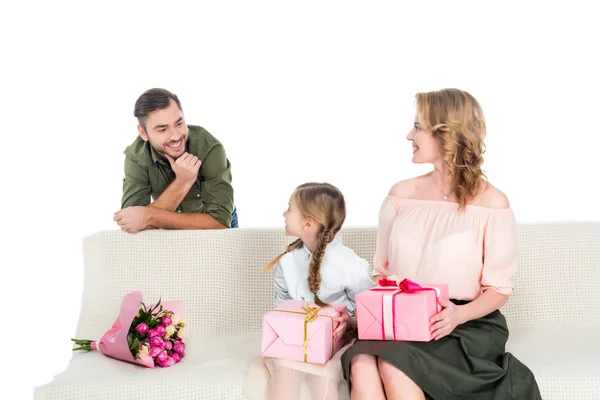 Homem olhando para a família feliz com presentes no sofá isolado no branco — Fotografia de Stock