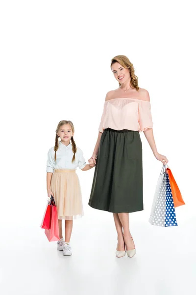 Élégante mère et fille avec des sacs à provisions tenant les mains isolées sur blanc — Photo de stock